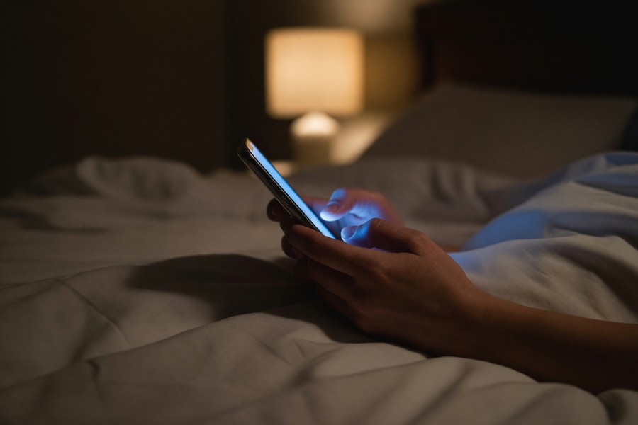 Person using a meditation app on a smartphone in a dimly lit bedroom at night
