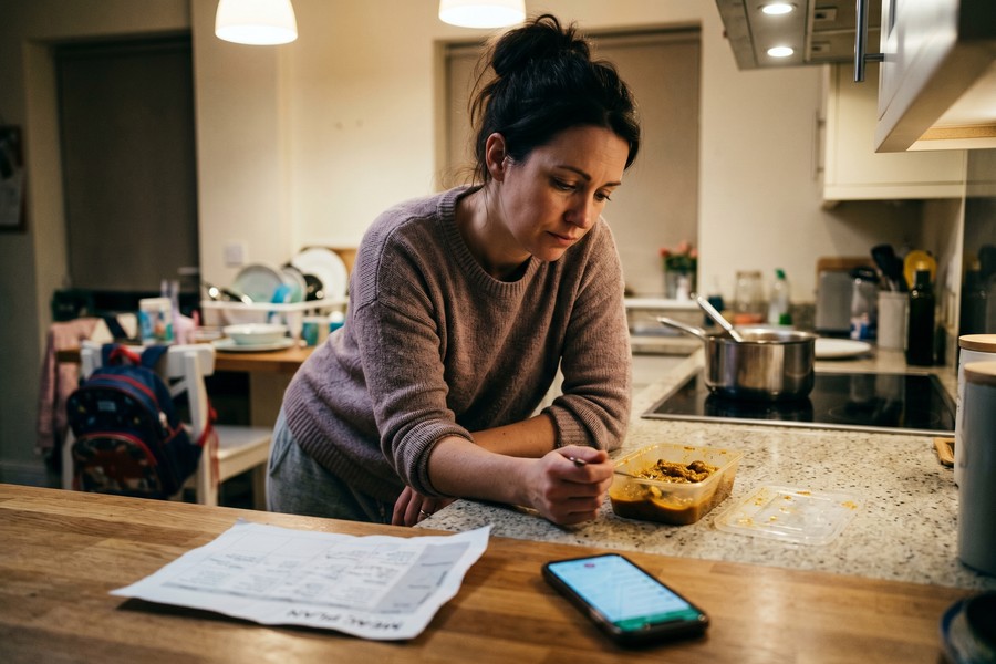 Person logging a meal in a nutrition app on a phone at a kitchen counter