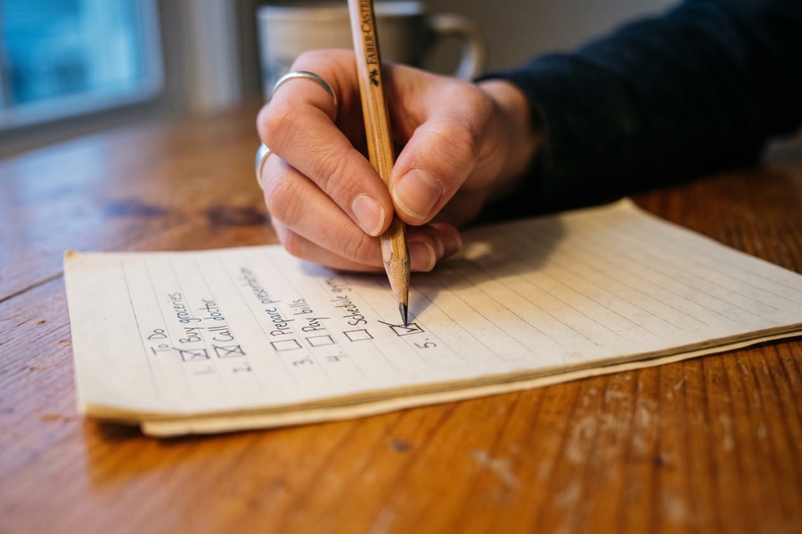 Person writing a short three-item priority list in a notebook the evening before work
