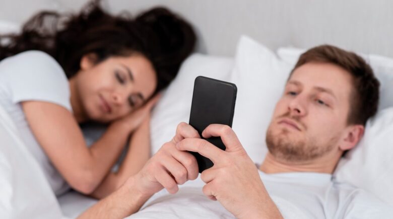 Couple in bed with sleep tracking app data displayed on smartphone